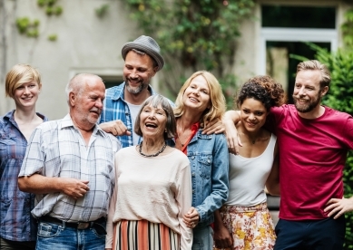 A man taking a group photo with his family and friends as a barbecue in a courtyard.