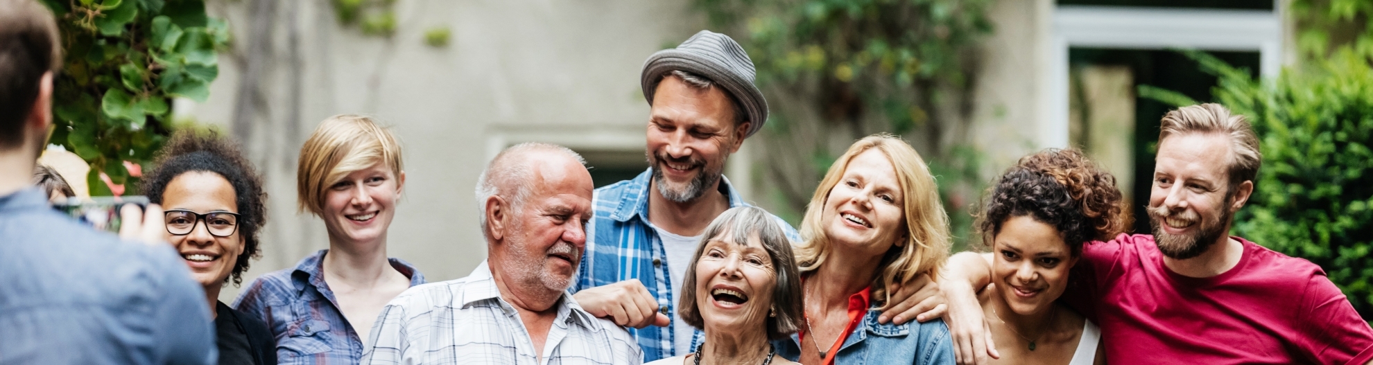 A man taking a group photo with his family and friends as a barbecue in a courtyard.